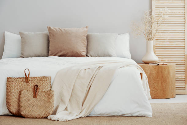 Linen bedding and a wool throw folded at the foot of a bed